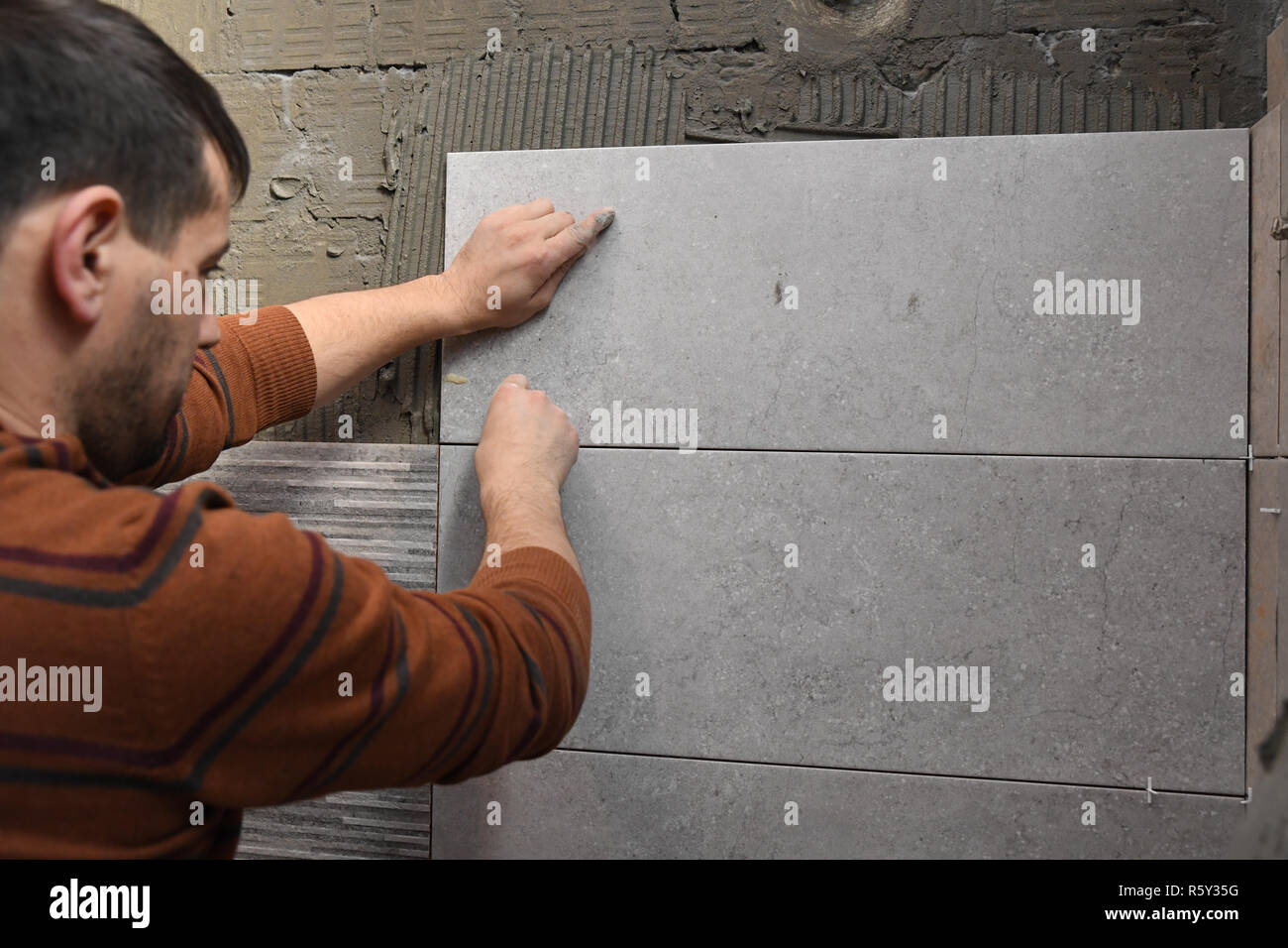 Gluing tiles on the wall. Laying tiles on the wall. Worker installing