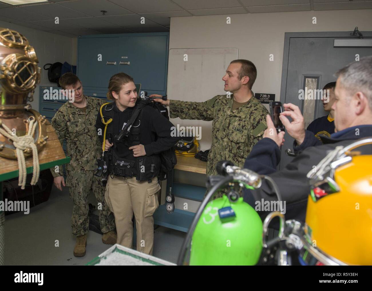 EVERETT, Wash. (April 20, 2017) Navy Diver 2nd Class Eric J. Lehman (Left) and Navy Diver 2nd Class Justin R. Rivere, assigned to the Puget Sound Navy Shipyard and Intermediate Maintenance Facility dive locker, demonstrate the weight of a self contained underwater breathing apparatus (SCUBA) during a Burlington-Edison High School Navy Junior Recruit Officer Training Command (JROTC) visit to the Navy dive locker at Naval Station Everett (NSE). While aboard NSE the Burlington-Edison High School JROTC toured the Navy dive locker, received a briefing on the use of a hyperbaric chamber and watched  Stock Photo