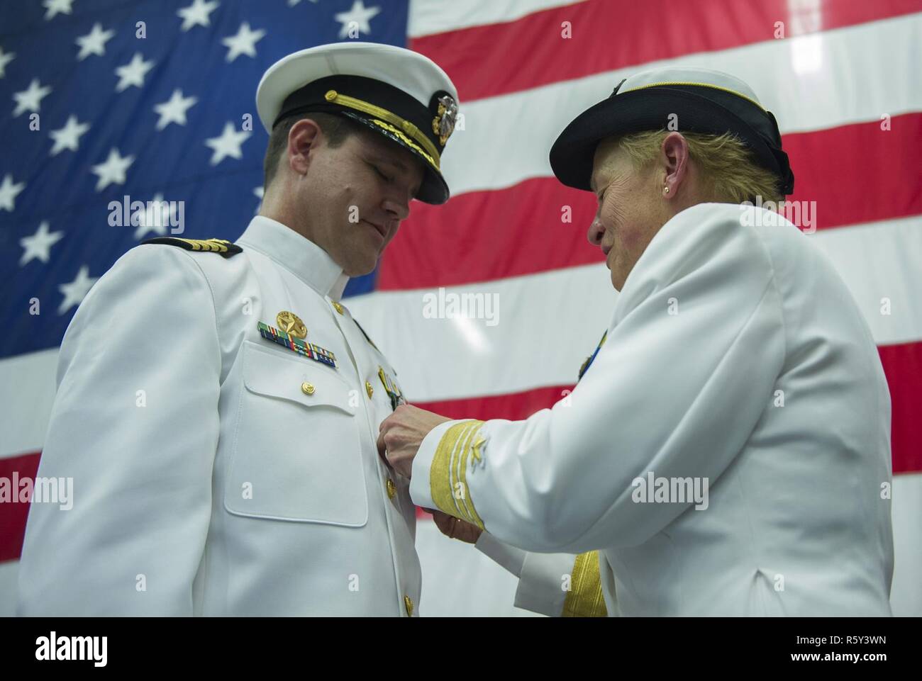 SAN DIEGO (April 20, 2017) Vice Adm. Nora Tyson, commander of U.S. 3rd fleet, presents an end-of-tour award to Capt. Homer Denius III, commander of Amphibious Squadron (PHIBRON) 3 during a change of command in the hangar bay aboard the amphibious assault ship USS America (LHA 6). America is an aviation centric amphibious assault ship that supports Marine aviation requirements, from small-scale contingency operations of an expeditionary strike group, to forcible entry missions in major theaters of war. Stock Photo