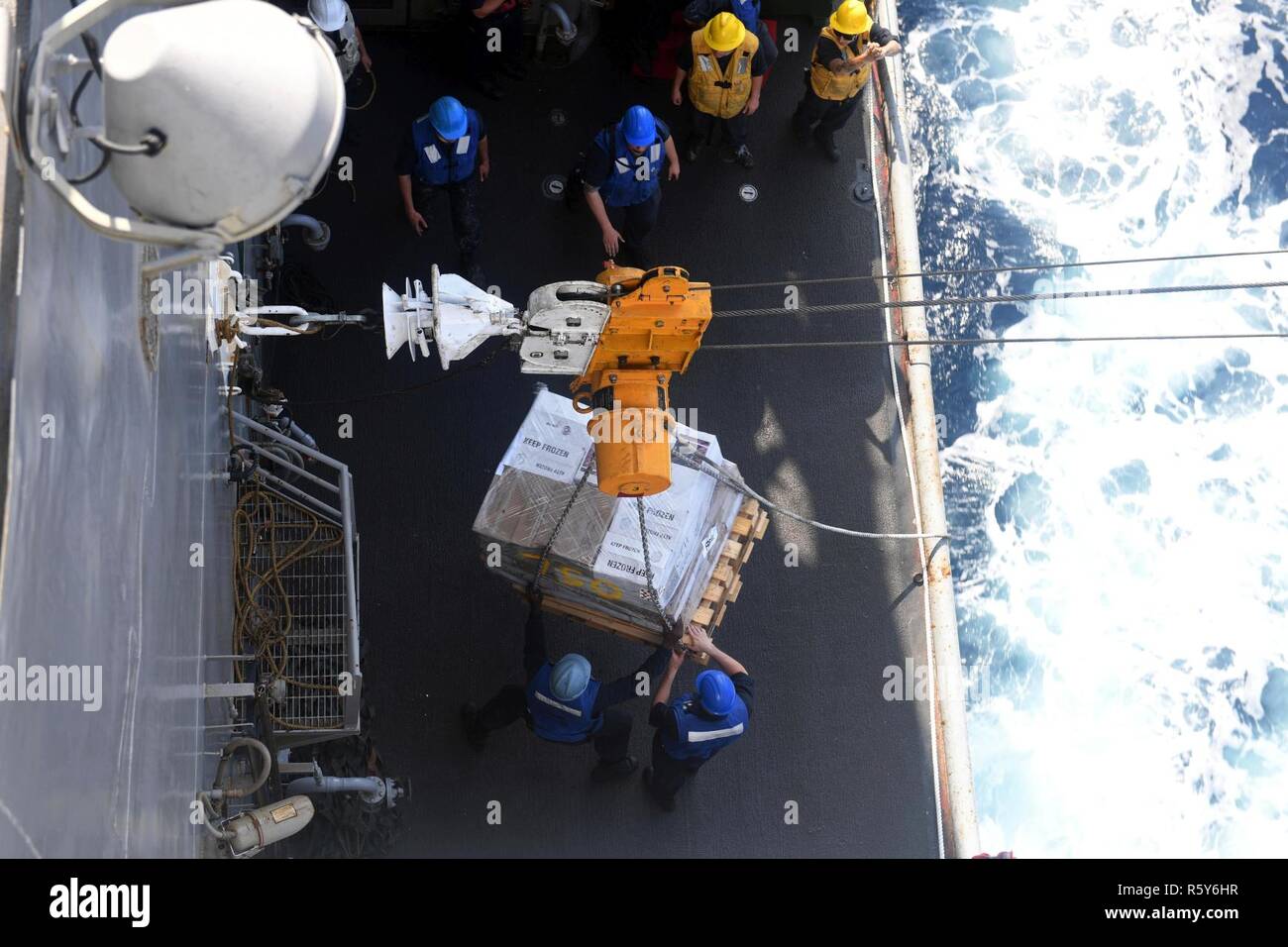 5TH FLEET AREA OF OPERATIONS (April 21, 2017) Sailors aboard the amphibious dock landing ship USS Carter Hall (LSD 50) control a pallet of supplies during an underway replenishment with the dry cargo and ammunition ship USNS Washington Chambers (T-AKE 11). Carter Hall, part of the Bataan Amphibious Ready Group, is deployed to the U.S. 5th Fleet area of operations in support of maritime security operations designed to reassure allies and partners, and preserve the freedom of navigation and the free flow of commerce in the region. Stock Photo