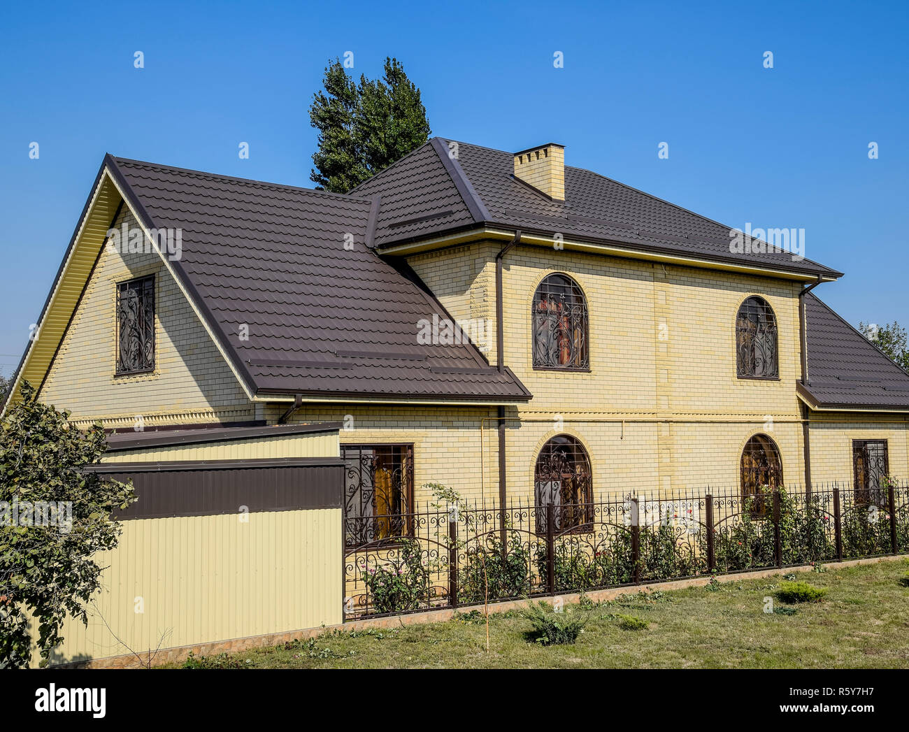 House Of Yellow Brick And Brown Corrugated Roof Made Of Metal Lattices On The Windows Stock Photo Alamy