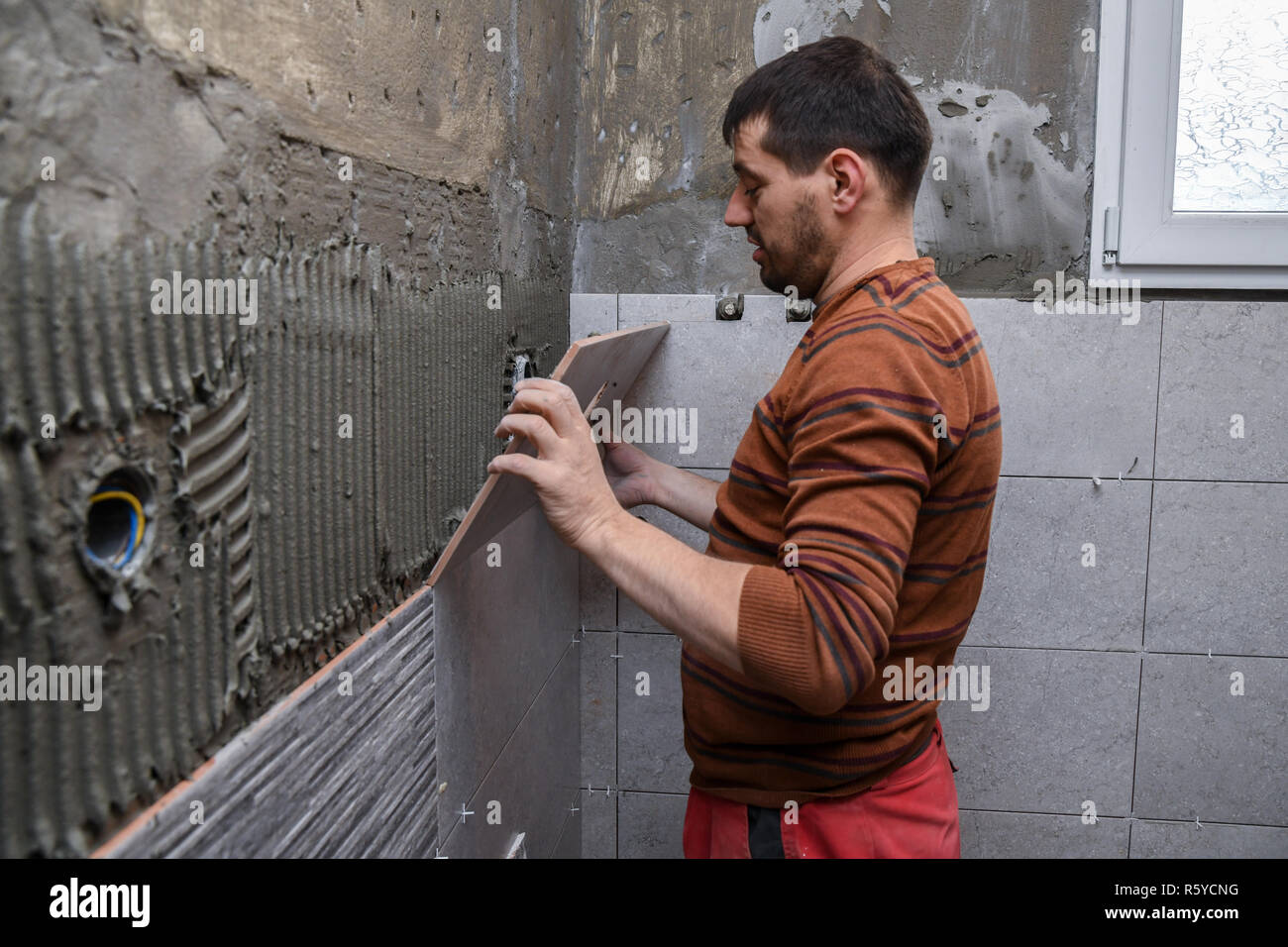 Gluing tiles on the wall. Laying tiles on the wall. Worker installing