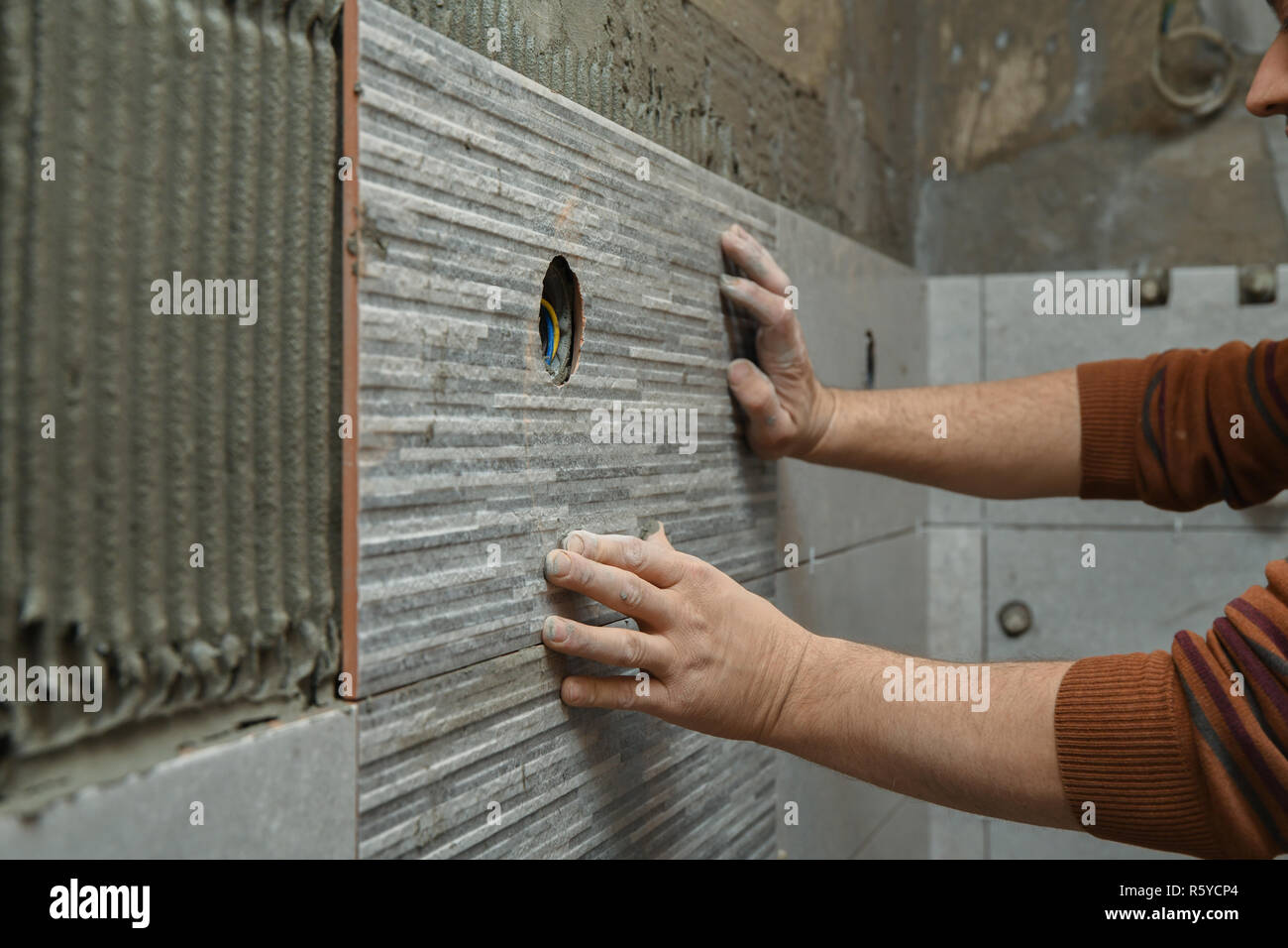 Gluing tiles on the wall. Laying tiles on the wall. Worker installing