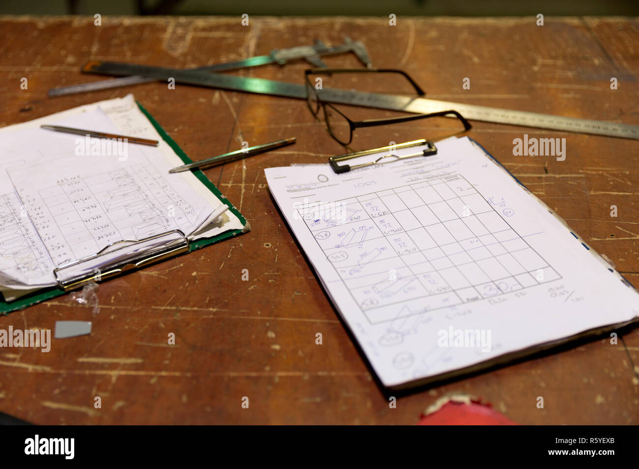 Clipboards with order notes on workshop table in metalwork factory Stock Photo