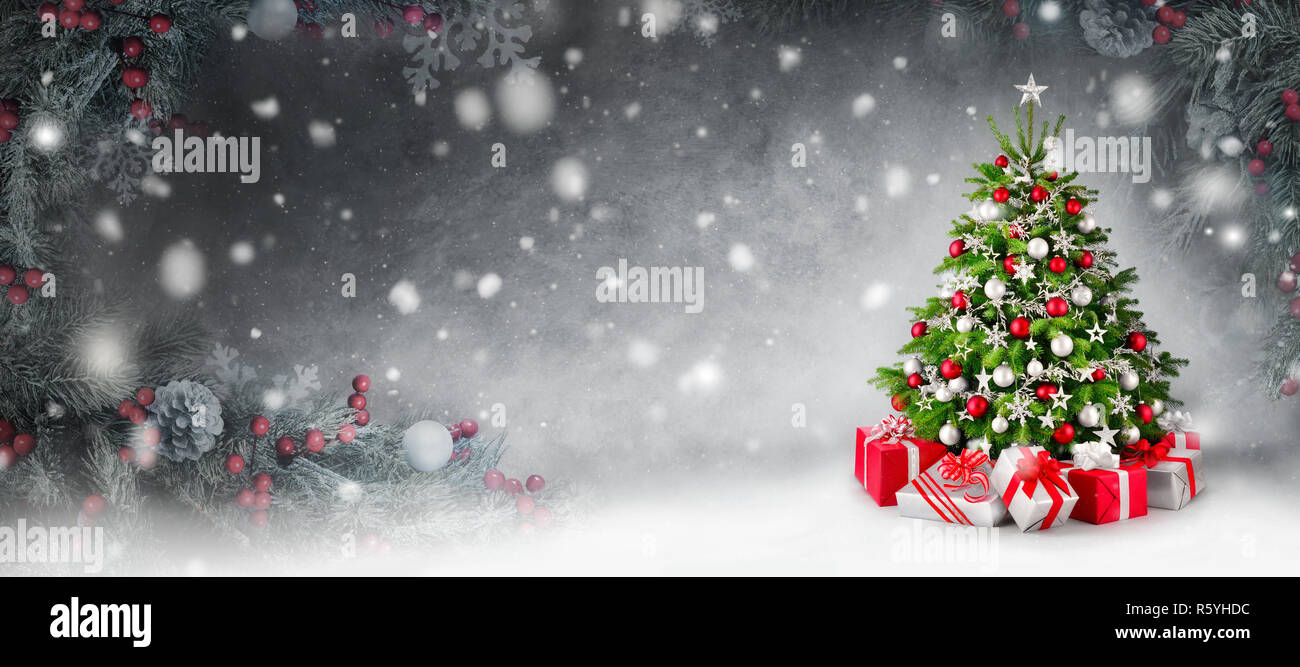 christmas background with christmas tree and presents in the snow,framed with fir branches Stock Photo