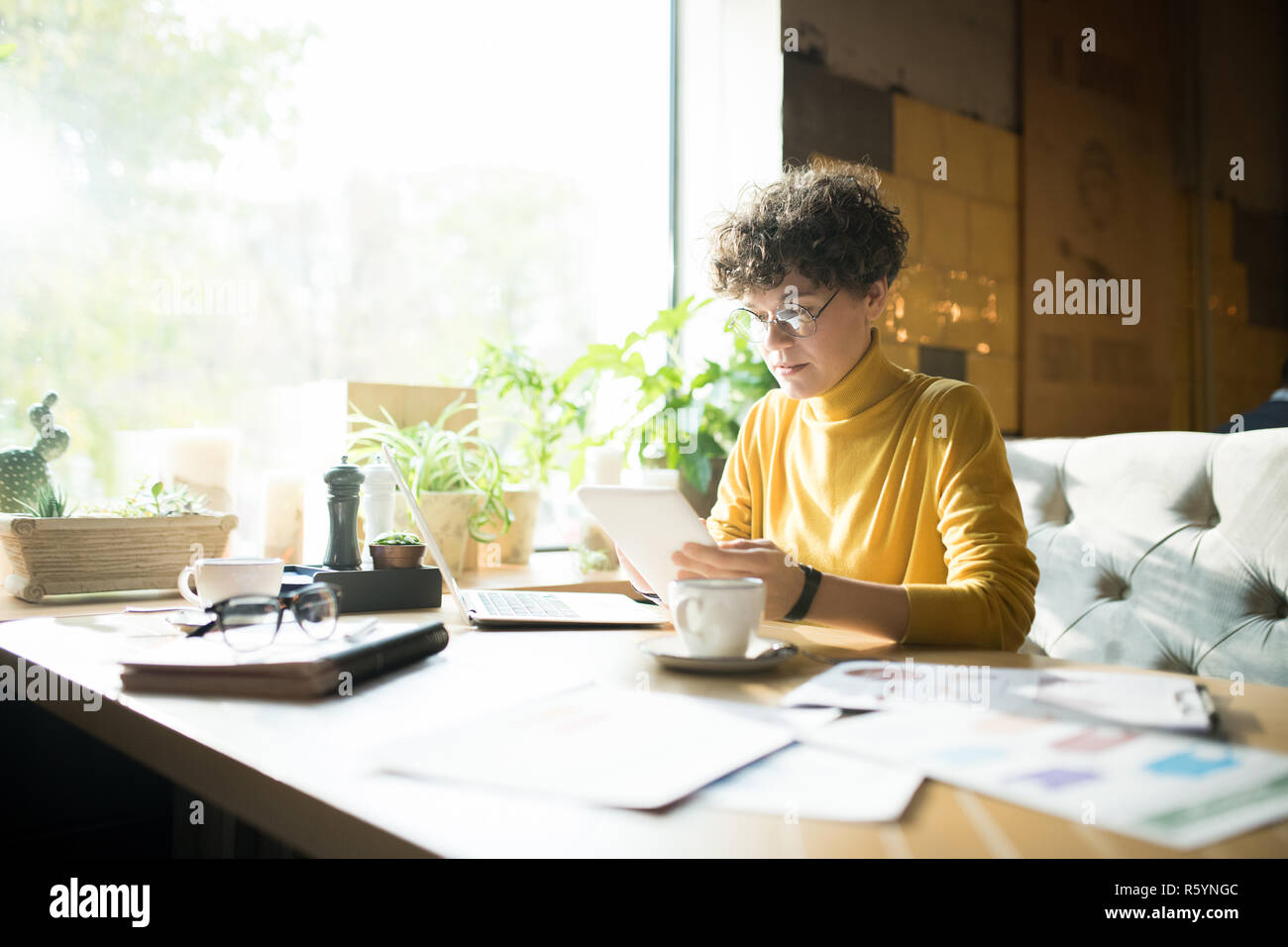 Serious woman in glasses working in cafe Stock Photo