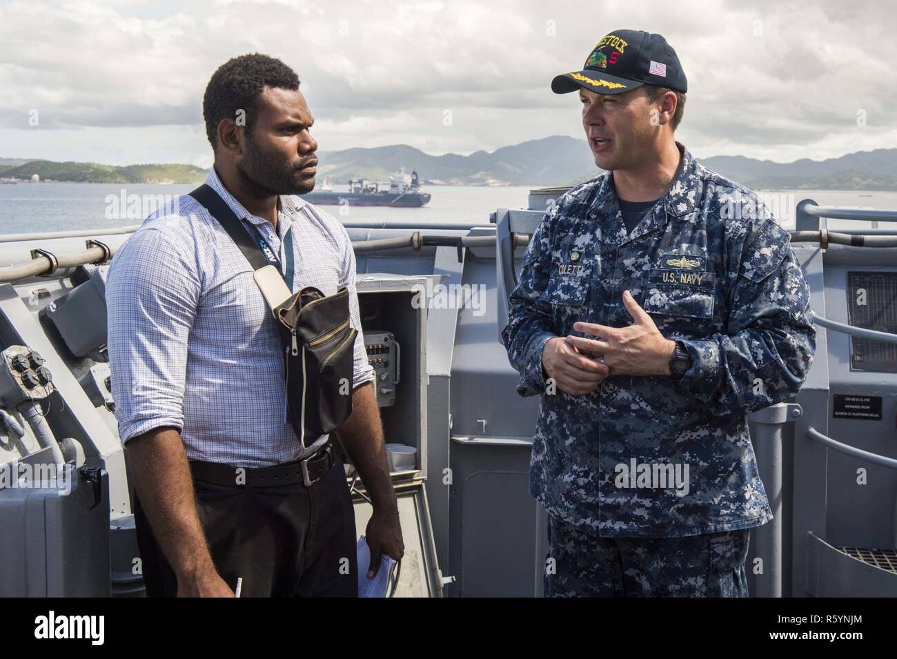 PORT MORESBY, Papua New Guinea (April 18, 2017) Cmdr. Bradley Coletti, right, commanding officer of the amphibious dock landing ship USS Comstock (LSD 45), speaks with a member of the media on the bridge wing during the ship’s visit to Papua New Guinea. Comstock, with the embarked 11th Marine Expeditionary Unit (11th MEU), is in Port Moresby to conduct activities and training that will enhance U.S.-Papua New Guinea relations as the two nations work together for a stable and prosperous Asia-Pacific region. Stock Photo