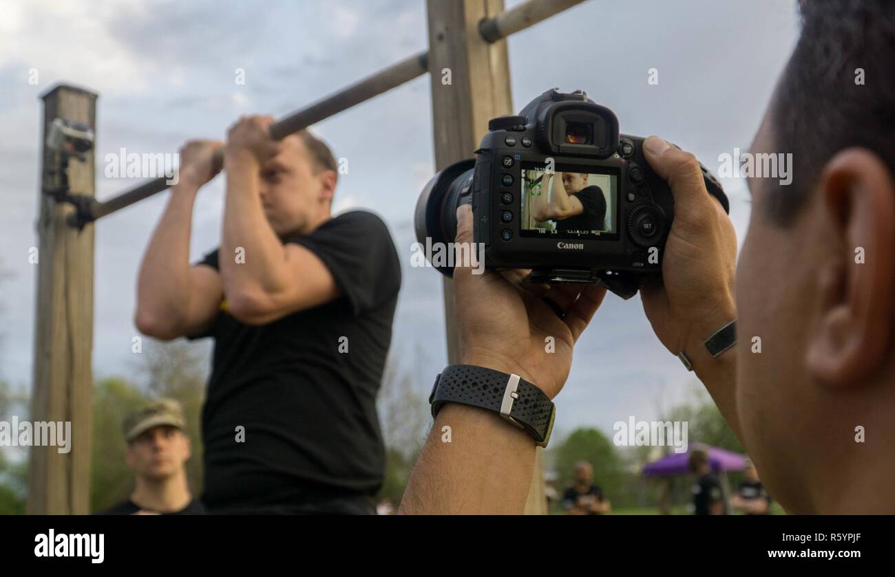 U.S. Army Staff Sgt. Sergio Rangel, assigned to the 982nd Combat Camera Company (Airborne), captures a video clip of Spc. William D. Lockwood, assigned to the 55th Signal Company (Combat Camera), executing 55 pull-ups during the Hilda Challenge in the 2017 5th Annual SPC Hilda I. Clayton Best Combat Camera (COMCAM) Competition at Fort George G. Meade, Md., April 17, 2017. Rangel is competing in the 2017 5th Annual Best COMCAM Competition where teams of two compete throughout a weeklong event that tests their physical, mental and technical capabilities. The Competition is established in honorin Stock Photo