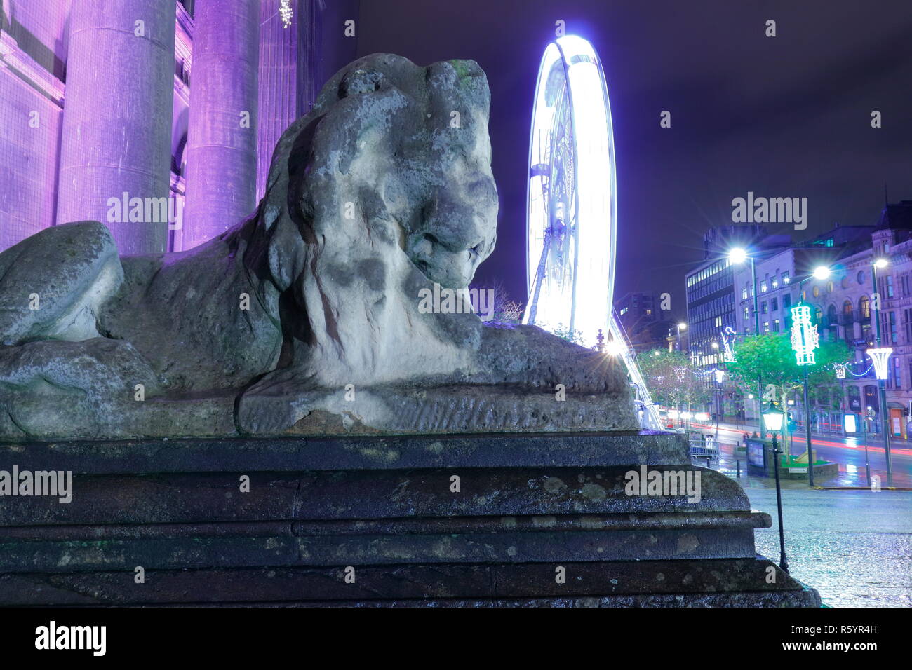 One of the Lions outside Leeds Town Hall with the Big Wheel tourist attraction.on the Headrow Stock Photo