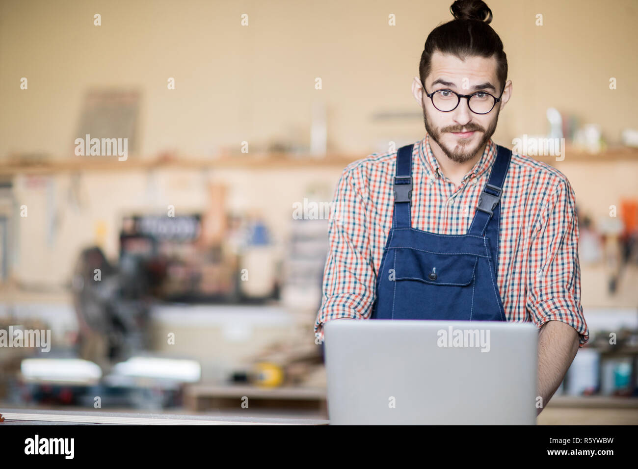 Contemporary Man using Laptop in Workshop Stock Photo