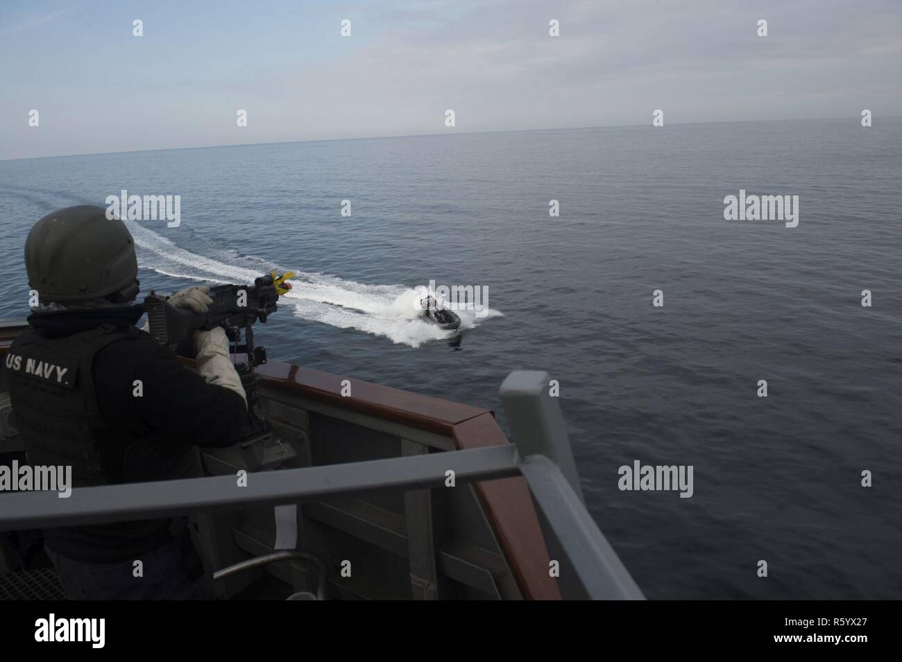 ATLANTIC OCEAN (April 20, 2017) - Gunner's Mate 2nd Class Cody Waliszewski mans a M240B machine gun aboard USS Carney (DDG 64) and repels a simulated hostile small craft while participating in Flag Officer Sea Training in the Atlantic Ocean April 20, 2017. Carney, an Arleigh Burke-class guided-missile destroyer, forward-deployed to Rota, Spain, is conducting its third patrol in the U.S. 6th Fleet area of operations in support of U.S. national security interests in Europe. Stock Photo
