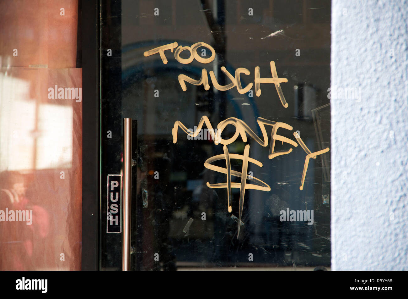 A spray-painted message is left on a glass door in Oakland, CA. Stock Photo