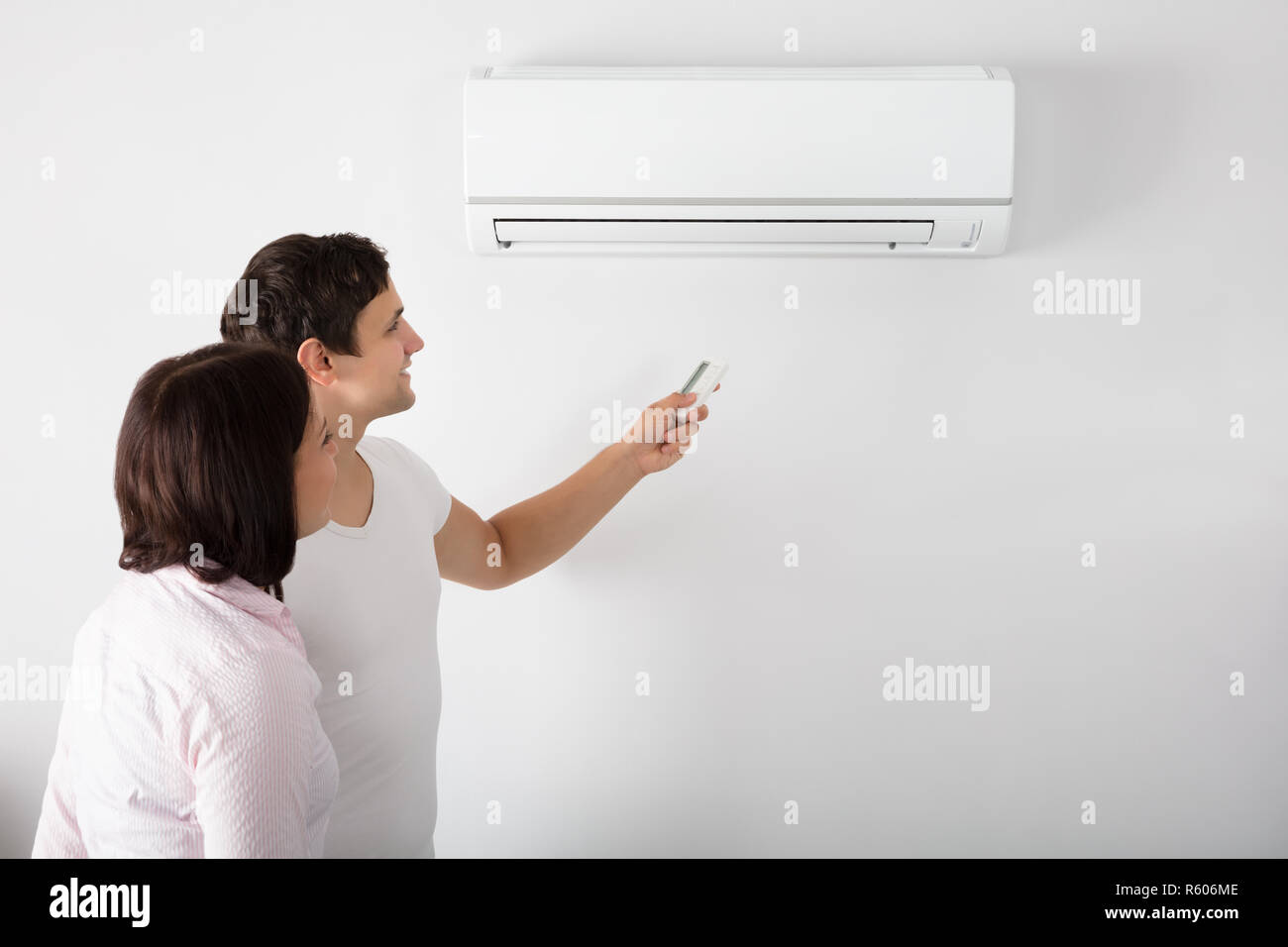 Couple Adjusting Temperature Of Air Conditioner Stock Photo Alamy