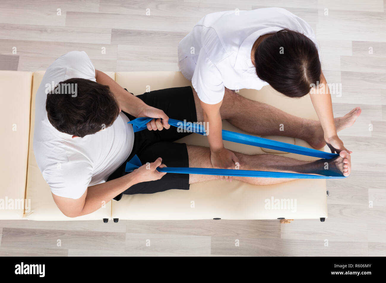 Female Therapist Assisting Patient While Exercising Stock Photo
