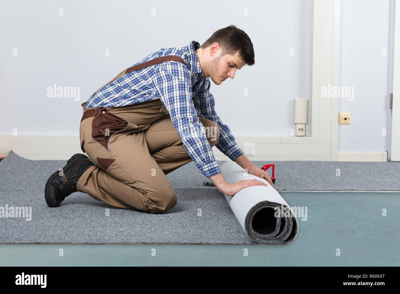 Male Handyman Rolling Carpet On Floor Stock Photo - Alamy