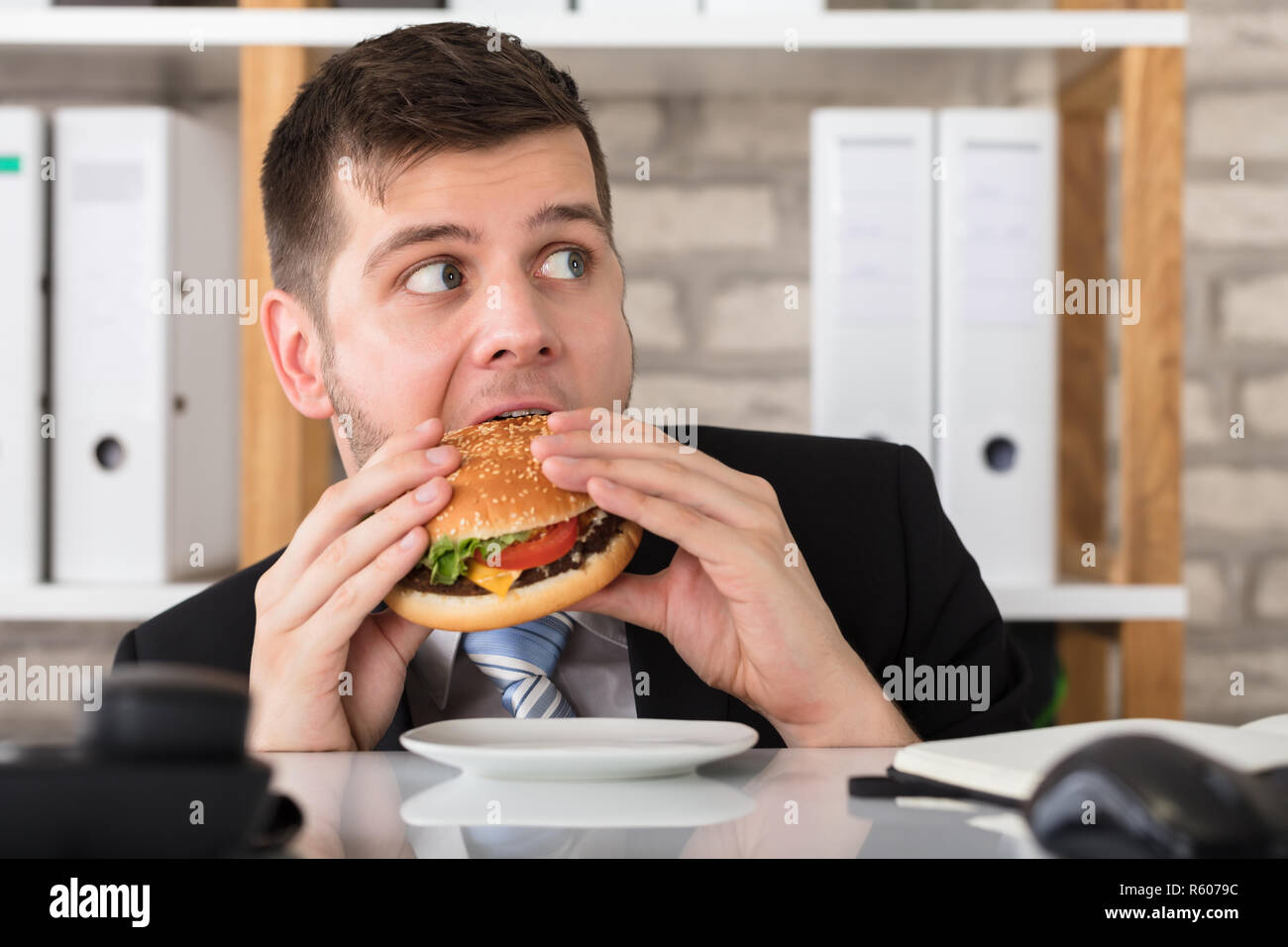Handsome Young Businessman Eating Burger Stock Photo