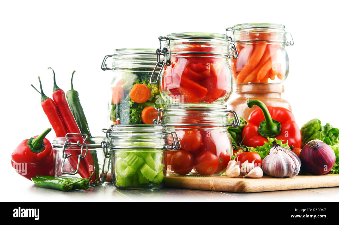Jars with marinated food and raw vegetables isolated on white Stock Photo