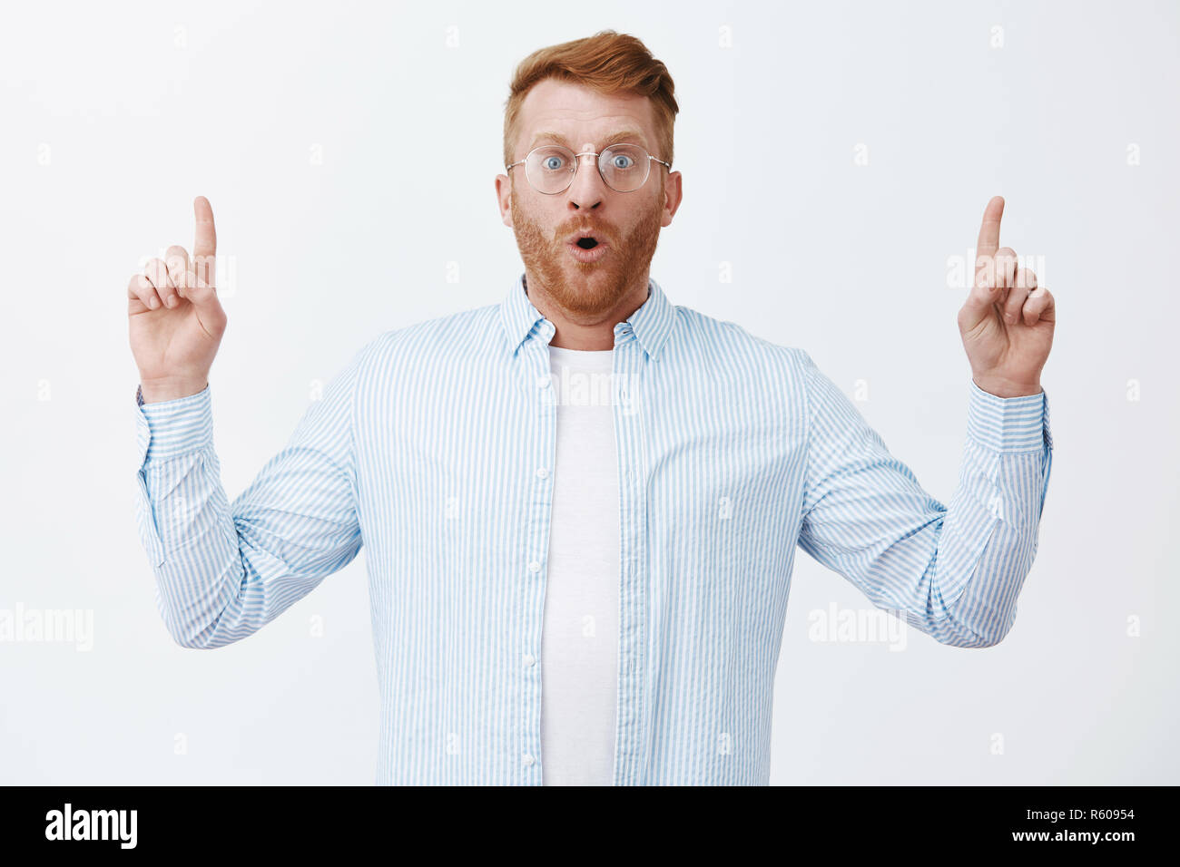 Losing words while looking at great business plan. Portrait of amazed and impressed excited redhead man with bristle, gasping, pointing up with raised Stock Photo