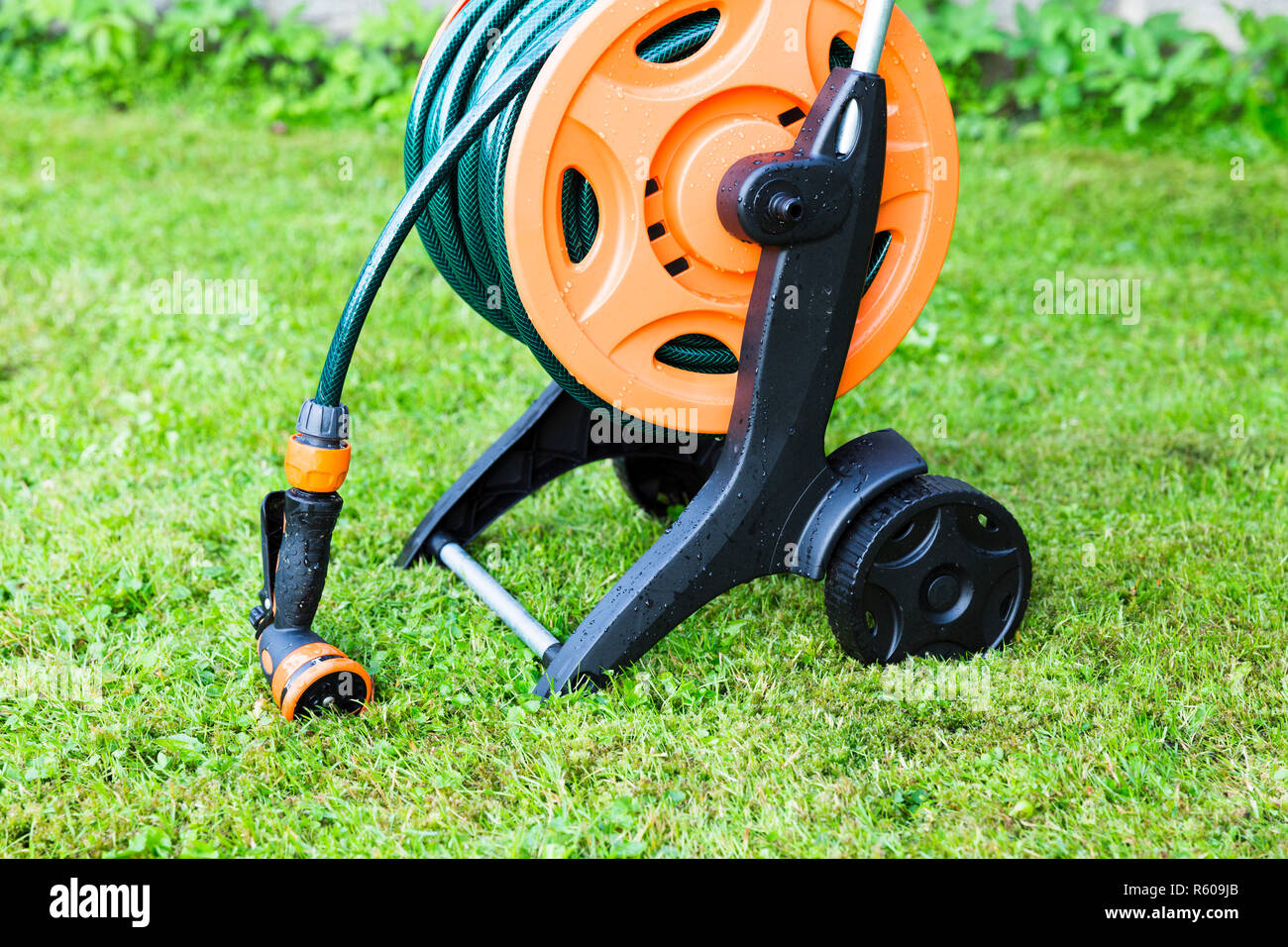 Coiled garden hose on reel, grass backgound Stock Photo Alamy