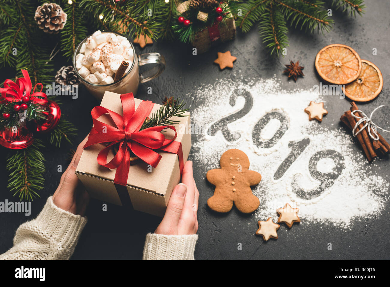Gift box and 2019 greeting written on flour. Female hands holding Christmas gift box Stock Photo