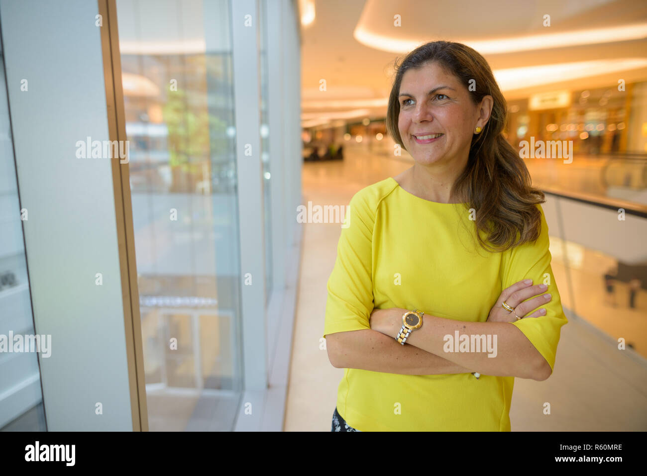 Portrait of happy mature woman thinking inside shopping mall Stock Photo