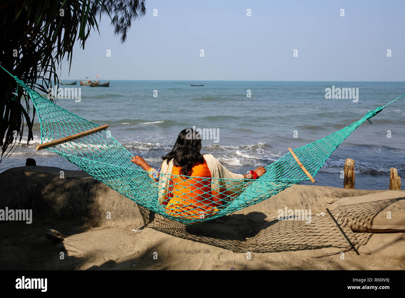 A lonely woman sits on a hammock beside a sea beach at Saint Martin Island. Cox’s Bazar, Bangladesh. Stock Photo