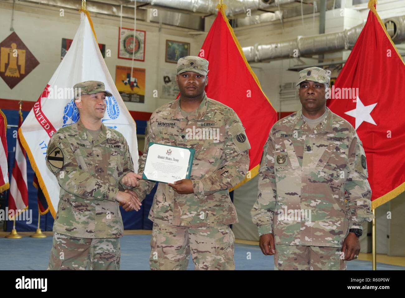 U.S. Army Brig. Gen. Stephen Hager (left), commander, 335th Signal Command, congratulates Army Spc. Deonte Monteria (center), automated logistical specialist, 978th Quartermaster Company, on continuing his commitment to the U.S. Army Reserves, April 22, at Camp Arifjan, Kuwait. The Army Reserve Engagement Cell hosted this annual event, as part of a celebratory day geared toward honoring the men and women who serve in the U.S. Army Reserves. Stock Photo