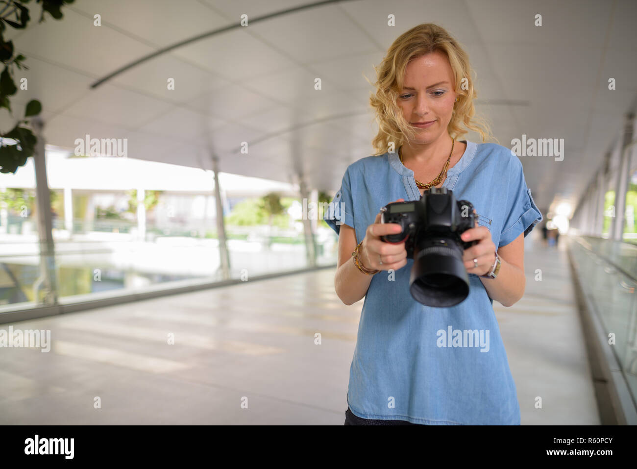 Beautiful blonde tourist woman photographer using camera outdoors Stock Photo