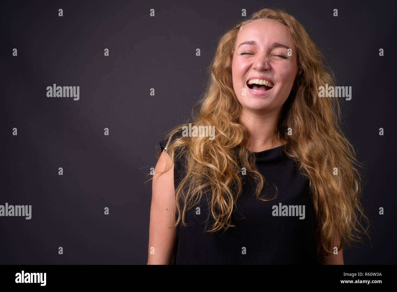 Beautiful young girl laughing. Pretty blonde with curly hair in