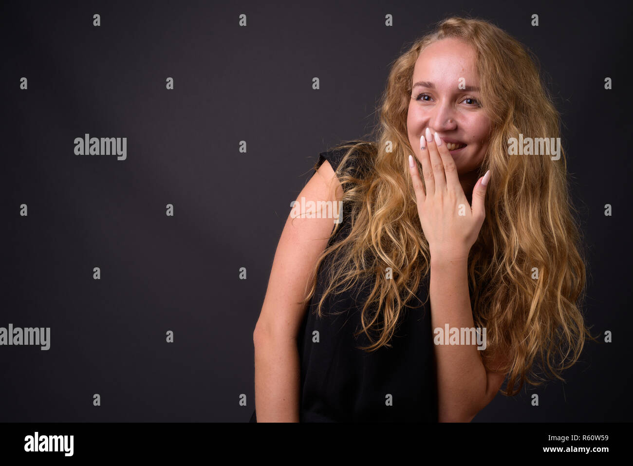 Young beautiful businesswoman with long wavy blond hair laughing Stock Photo