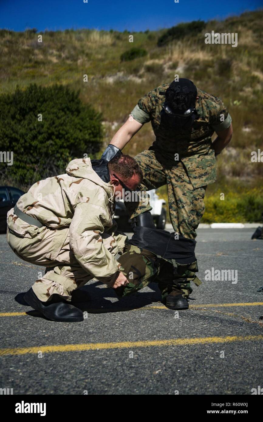 U.S. Marine Staff Sgt. Philip Barnes helps a student take off their Mission Oriented Protective Posture suit as part of the Reconnaissance, Surveillance and Decontamination training aboard Marine Corps Base Camp Pendleton, Calif., April 26, 2017. The purpose of this training is to accomplish missions within a chemical, biological, radiological and nuclear environment.  Barnes is the CBRN chief for 1st Maintenance Battalion, 1st Marine Logistics Group. Stock Photo