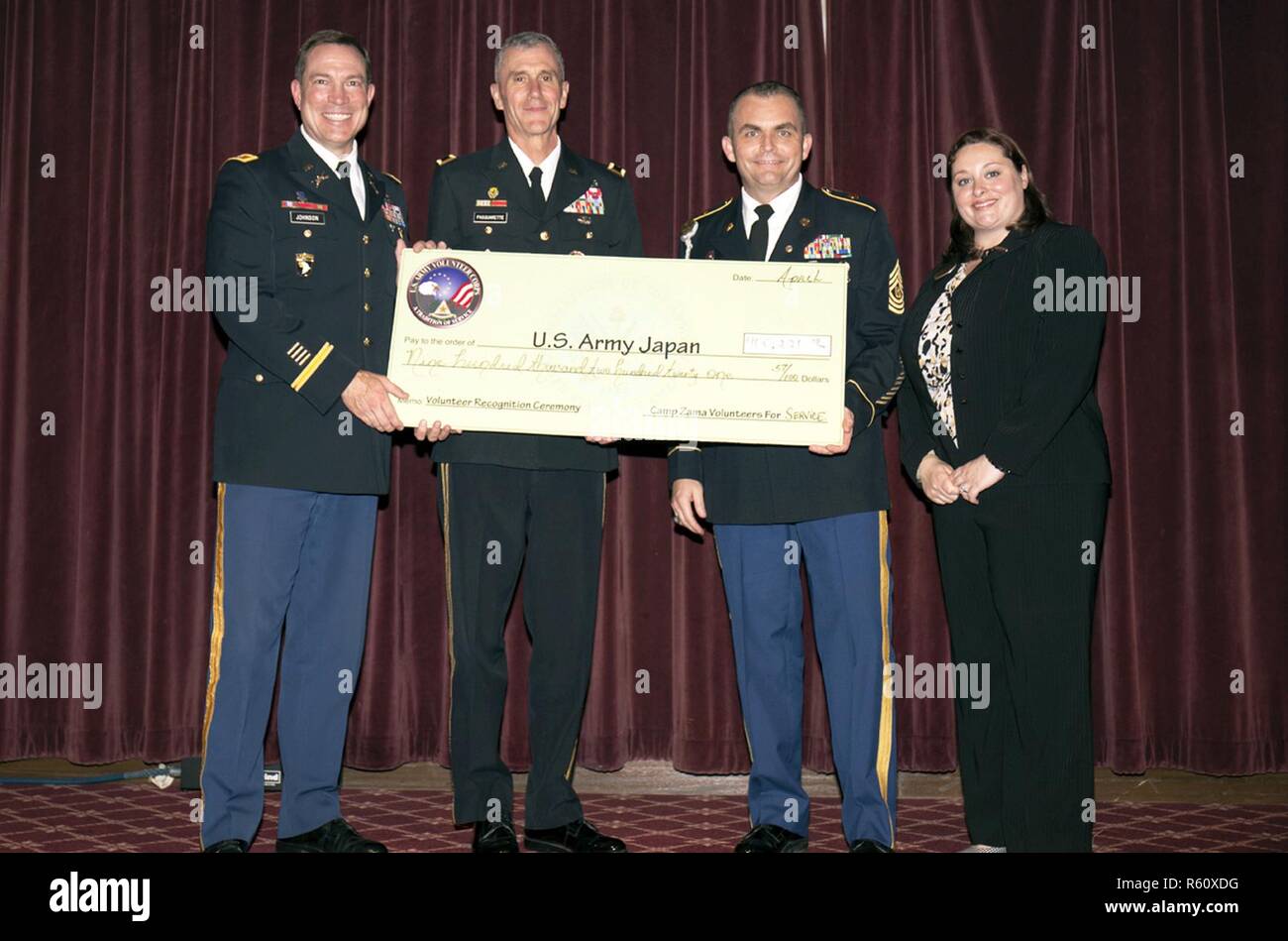 U.S. Army Japan and Garrison Japan leaders display a check for $900,221.57, the amount saved in the past year by the hard work volunteers performed during the year during Camp Zama's annual Volunteer Recognition Ceremony April 21 at the Camp Zama Community Club. Stock Photo