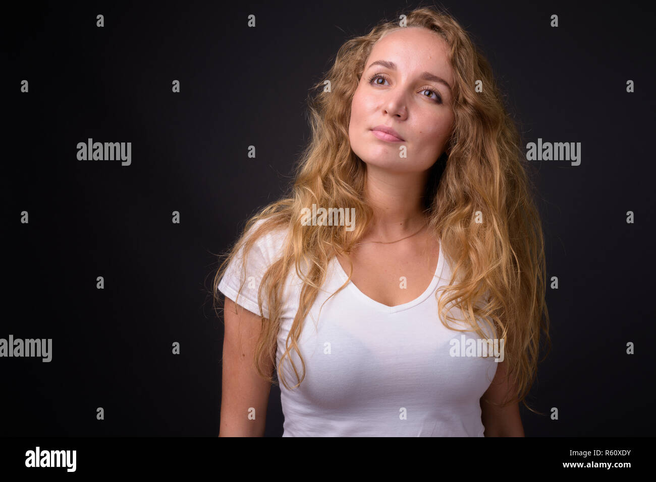 Young beautiful woman with long wavy blond hair thinking Stock Photo