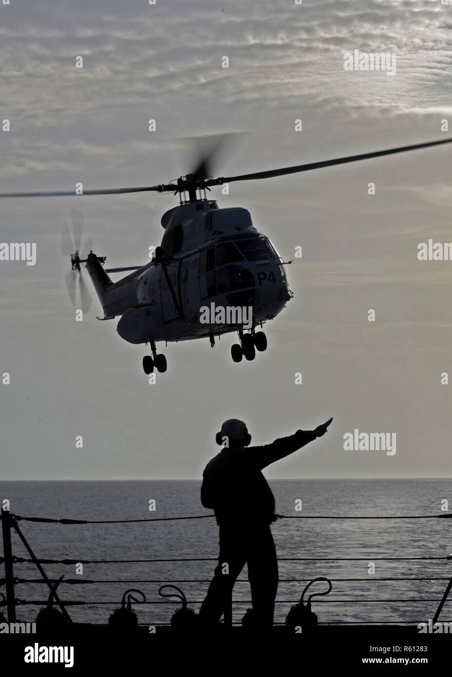 U.S. 5TH FLEET AREA OF OPERATIONS (April 30, 2017) Boatswain’s Mate 2nd Class Daniel Martinez-Lebron signals to an AS-332 Super Puma helicopter after launching from the flight deck of the guided-missile destroyer USS Truxtun (DDG 103) during a vertical replenishment with Military Sealift Command fleet replenishment oiler USNS Washington Chambers (T-AKE 11). Truxtun is deployed to the U.S. 5th Fleet area of operations in support of maritime security operations designed to reassure allies and partners and preserve the freedom of navigation and the free flow of commerce in the region. Stock Photo
