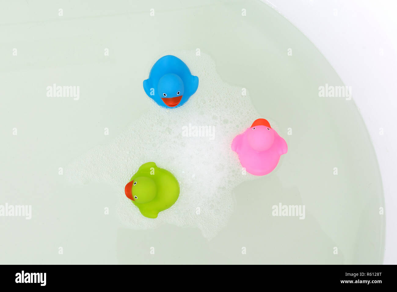 Pink, green and blue duck in a bathtub, surrounded by soap Stock Photo ...