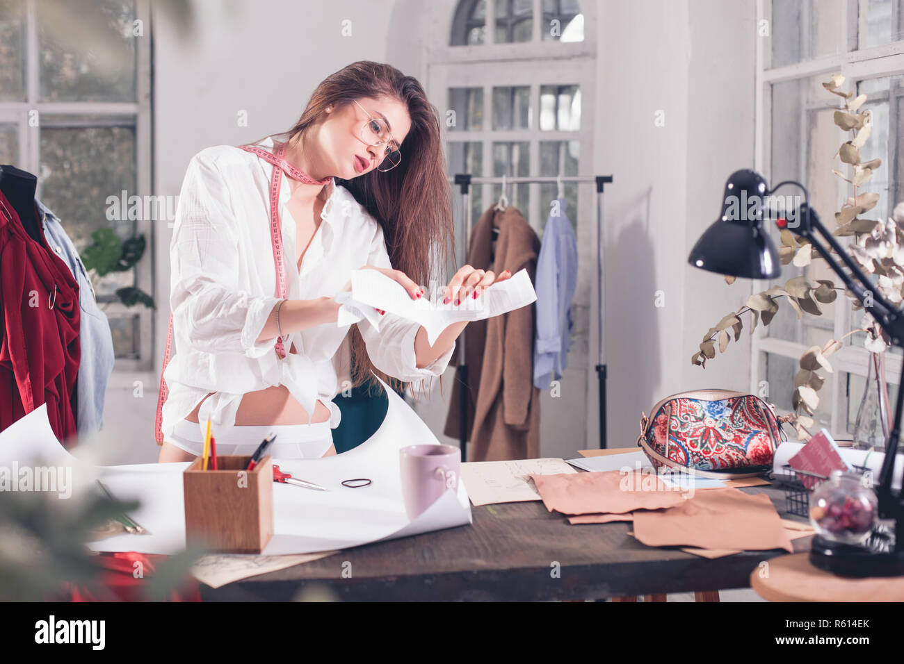 Fashion designers working in studio sitting on the desk Stock Photo - Alamy