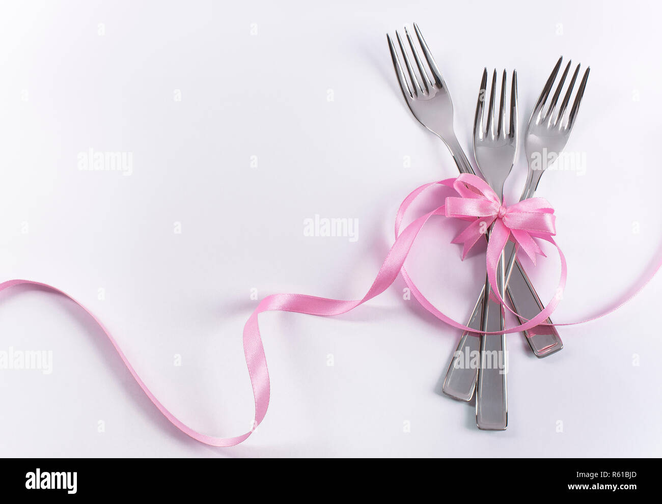 Silverware on white with pink ribbon as background for menu and invitation Stock Photo