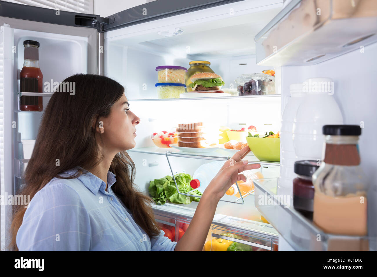 Young Woman Looking At Food In Refrigerator Stock Photo