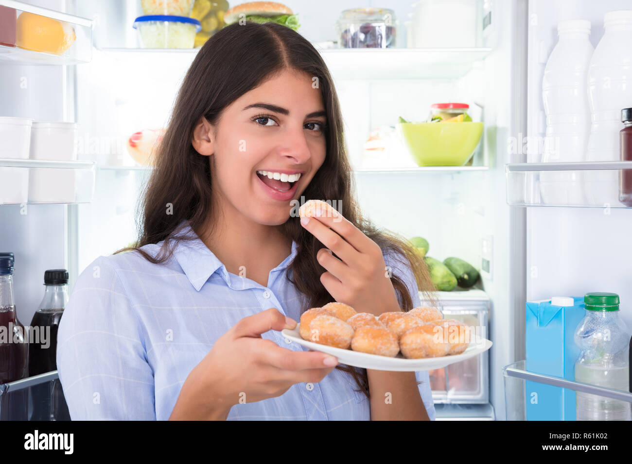 Smiling Woman Eating Cookies In Plate Stock Photo