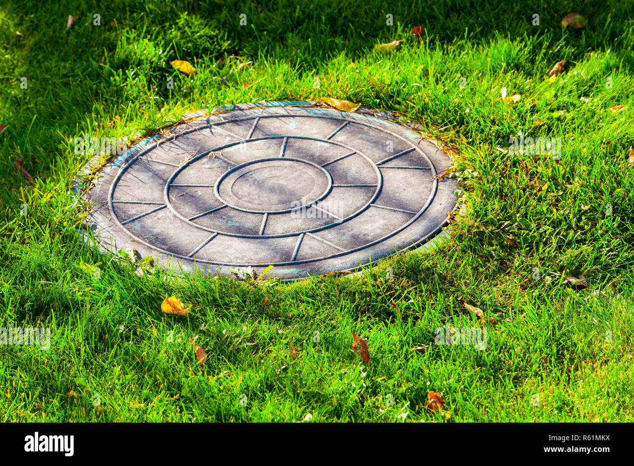 Sewer manhole on a green lawn. Stock Photo