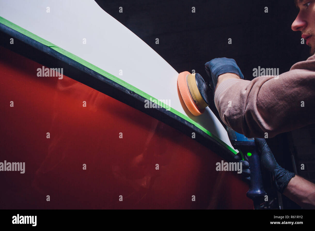 Yacht maintenance. Man polishing side boat polishing grinder machine in