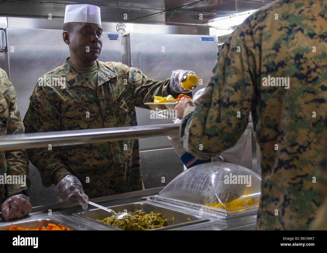 1st Sergeant Yancey Pascall serves corn on the cob to a Marine during the Thanksgiving celebration aboard San Antonio-class amphibious transport dock ship USS Somerset (LPD 25) Nov. 21, 2018, while underway in the Pacific Ocean. USS Somerset is part of Littoral Combat Group One, which is deployed in support of the Enduring Promise Initiative to reaffirm U.S. Southern Command’s longstanding commitment to the nations of the Western Hemisphere. Stock Photo