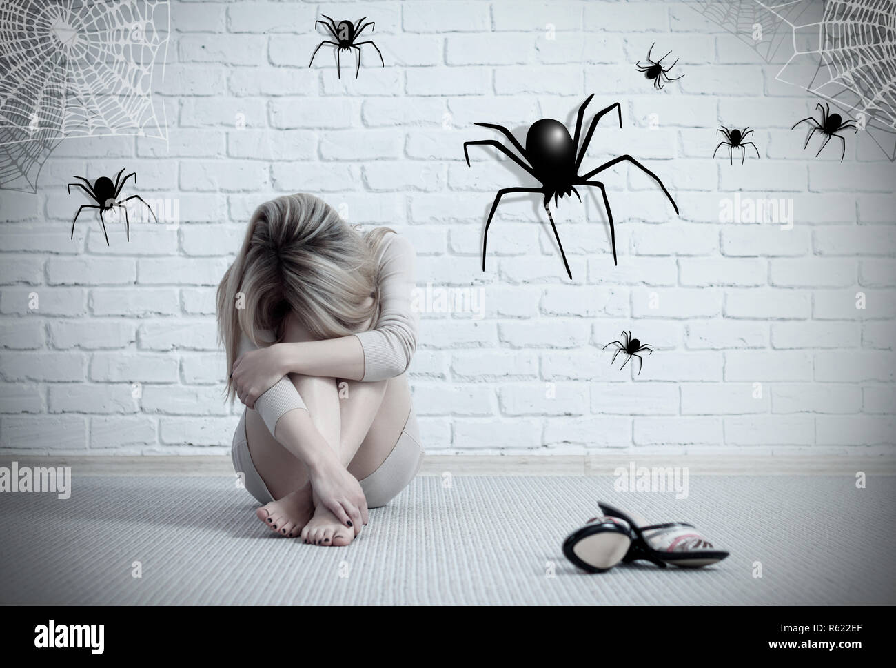 Woman sitting on the floor and looking on imaginary spider. Stock Photo