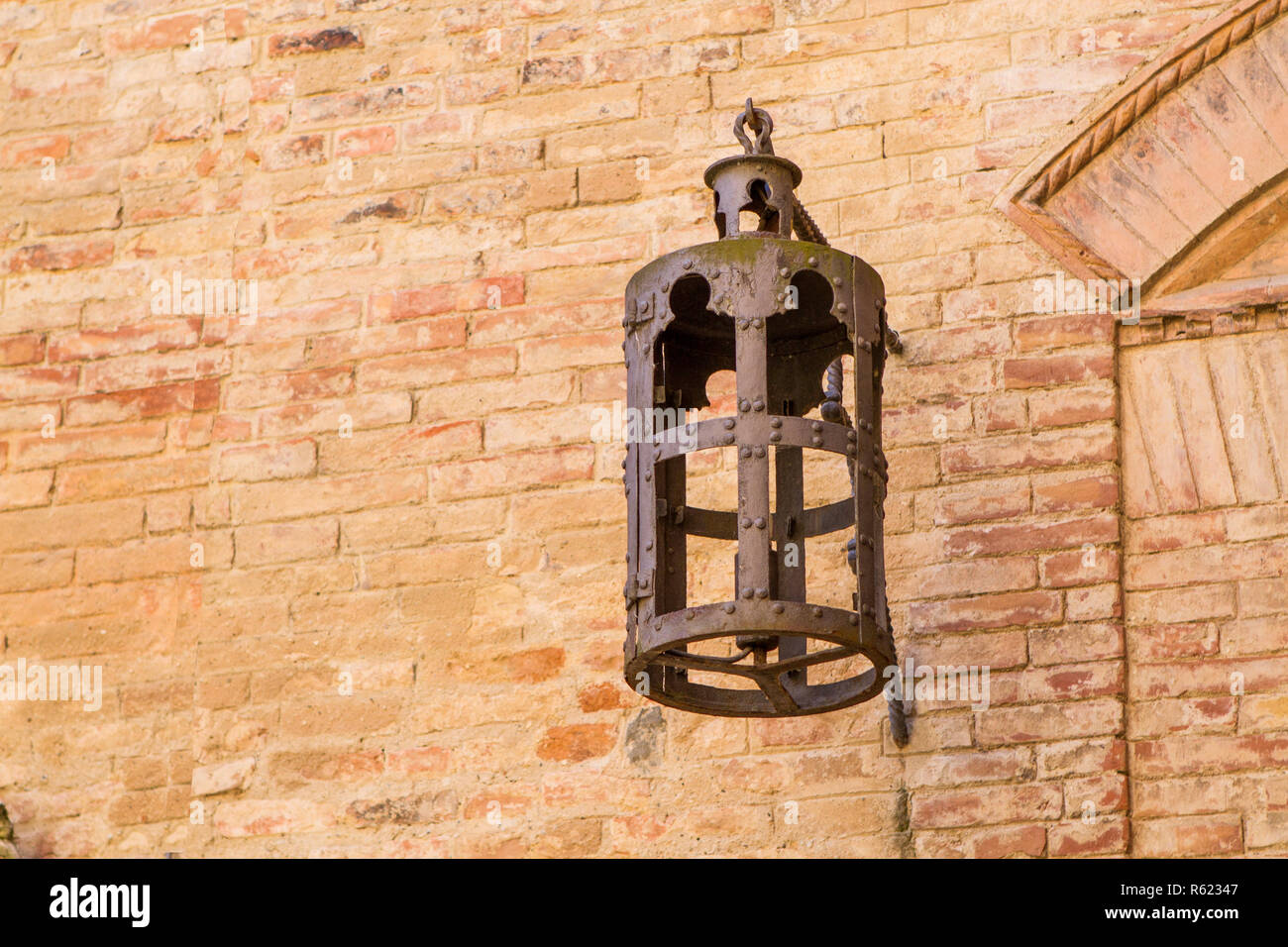 antique iron street lamp on the stone wall of a medieval house in tuscany,italy. Stock Photo