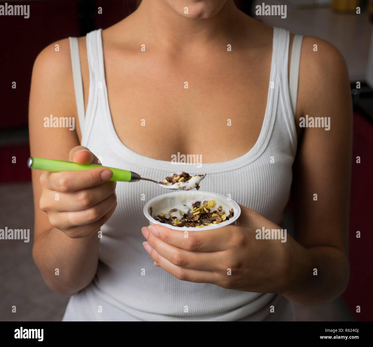 young woman eating yogurt with cornflakes Stock Photo