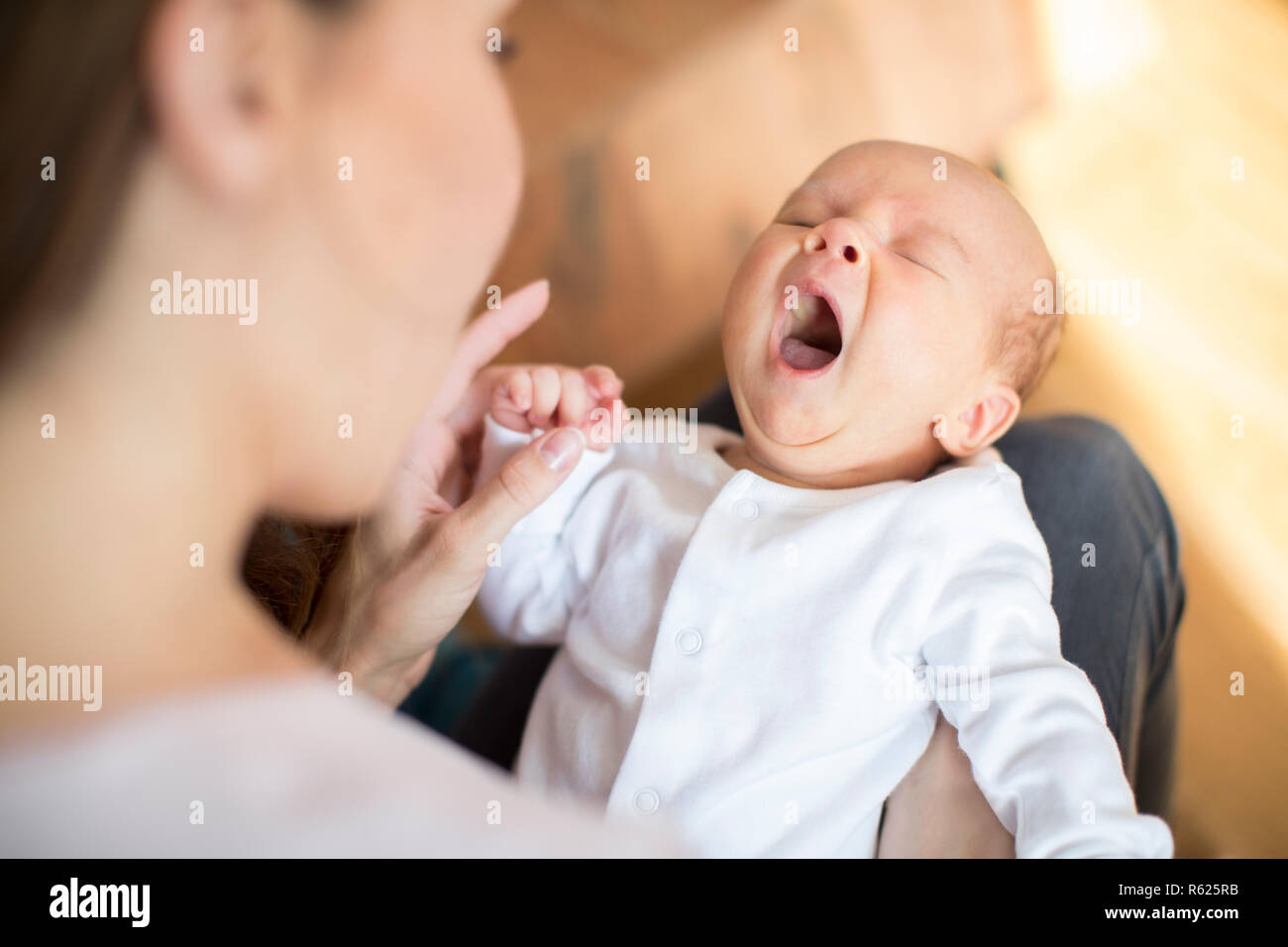 Overhead View Of Mother Cuddling Yawning Newborn Baby Son At Home Stock Photo