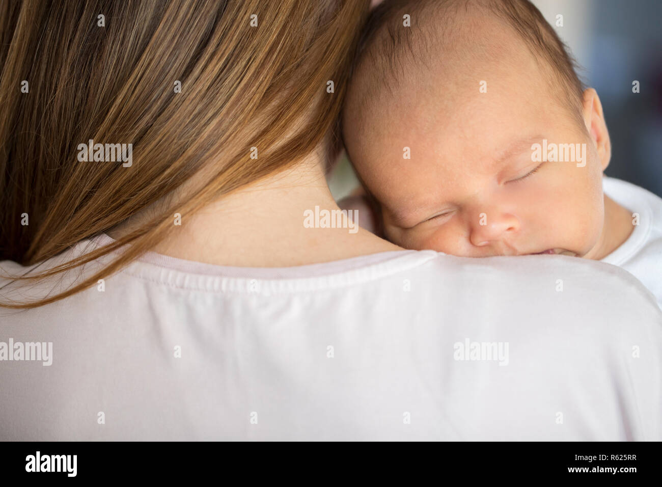 Loving Mother Cuddling Sleeping Newborn Baby Son Over Shoulder Stock Photo