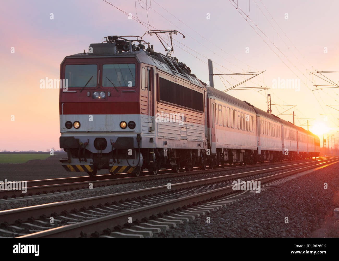 Passenger train on railway at sunset Stock Photo