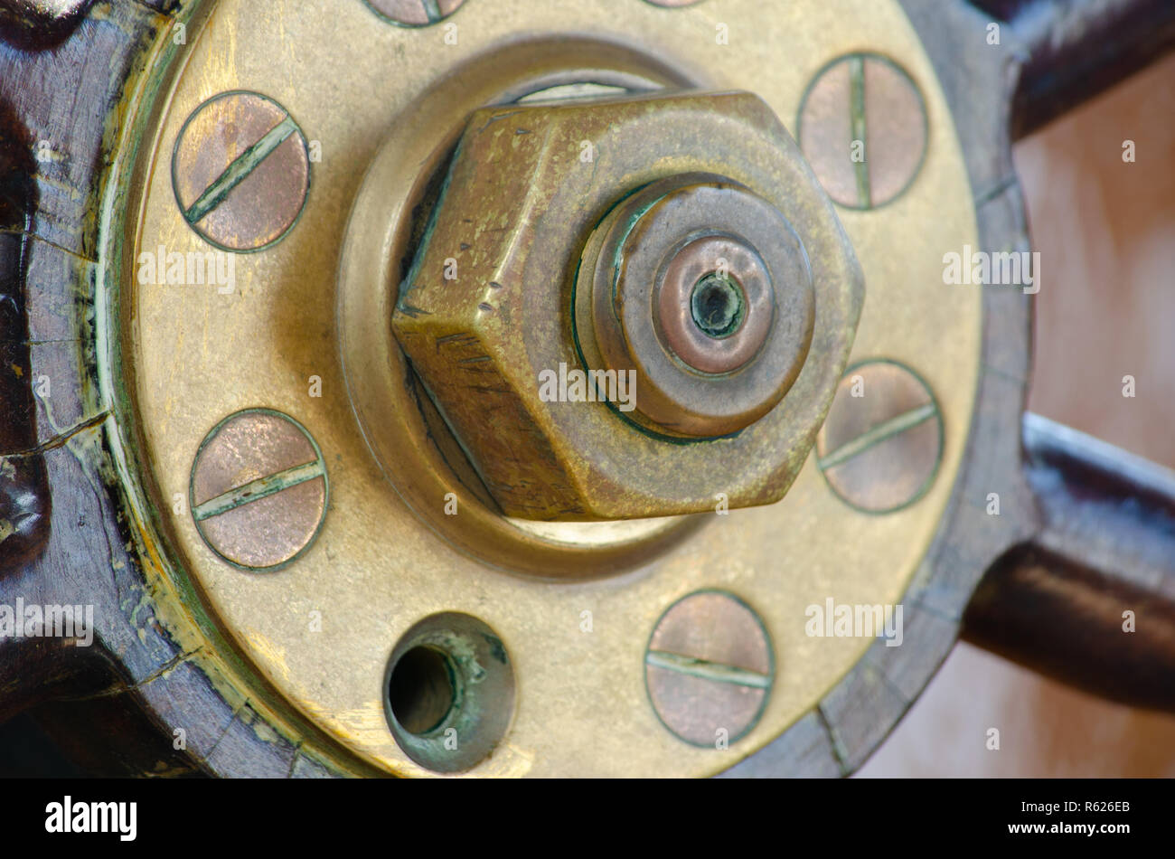 An old wood, copper and brass ship's wheel with a missing screw. Stock Photo