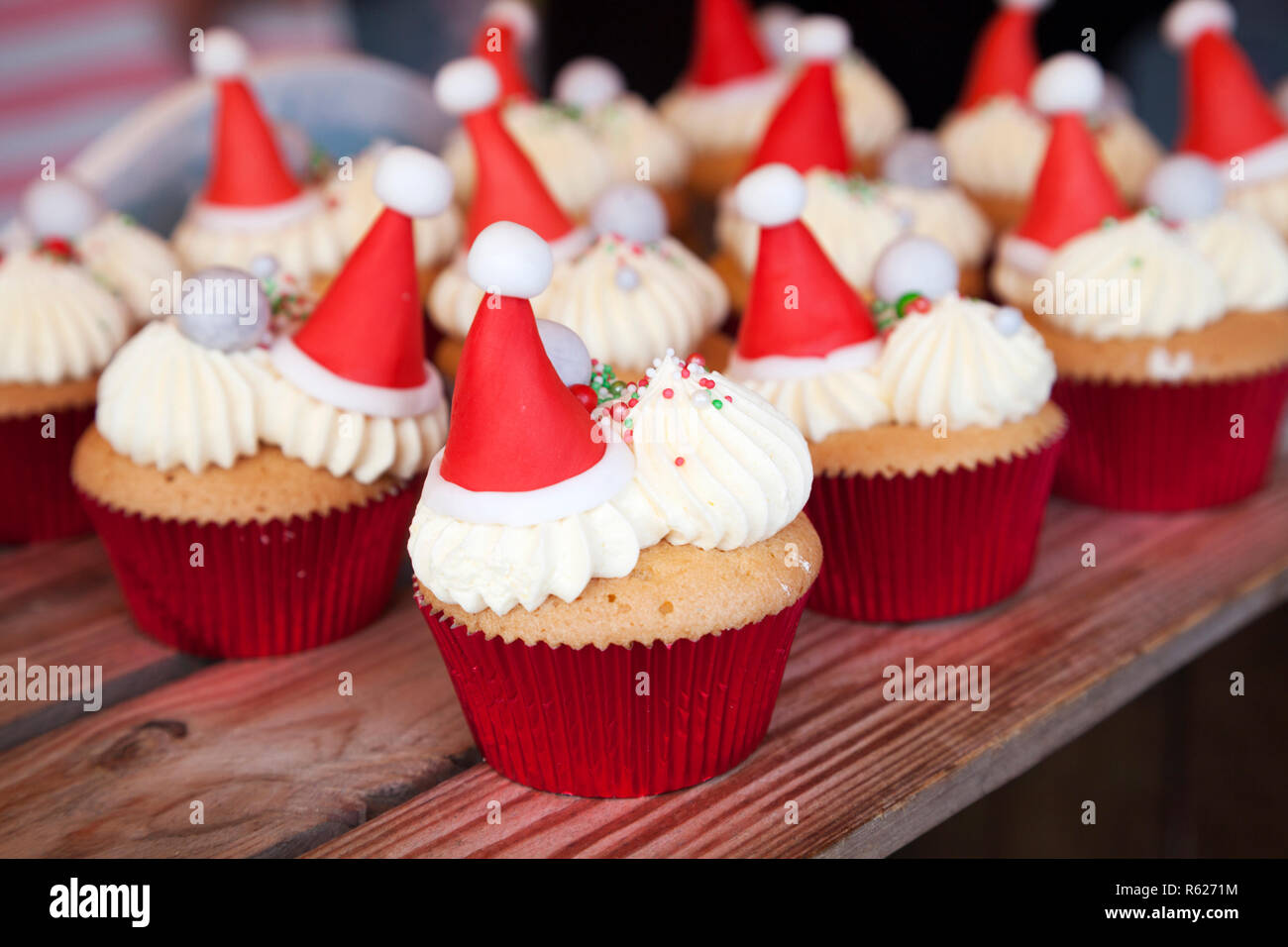 Cup cakes decorated with cream, iced Santa hats and sprinkles Stock Photo